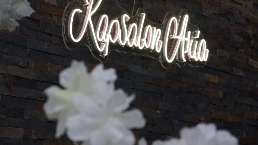 Neon reclame Kapsalon Aria op de stenen muur in de shop