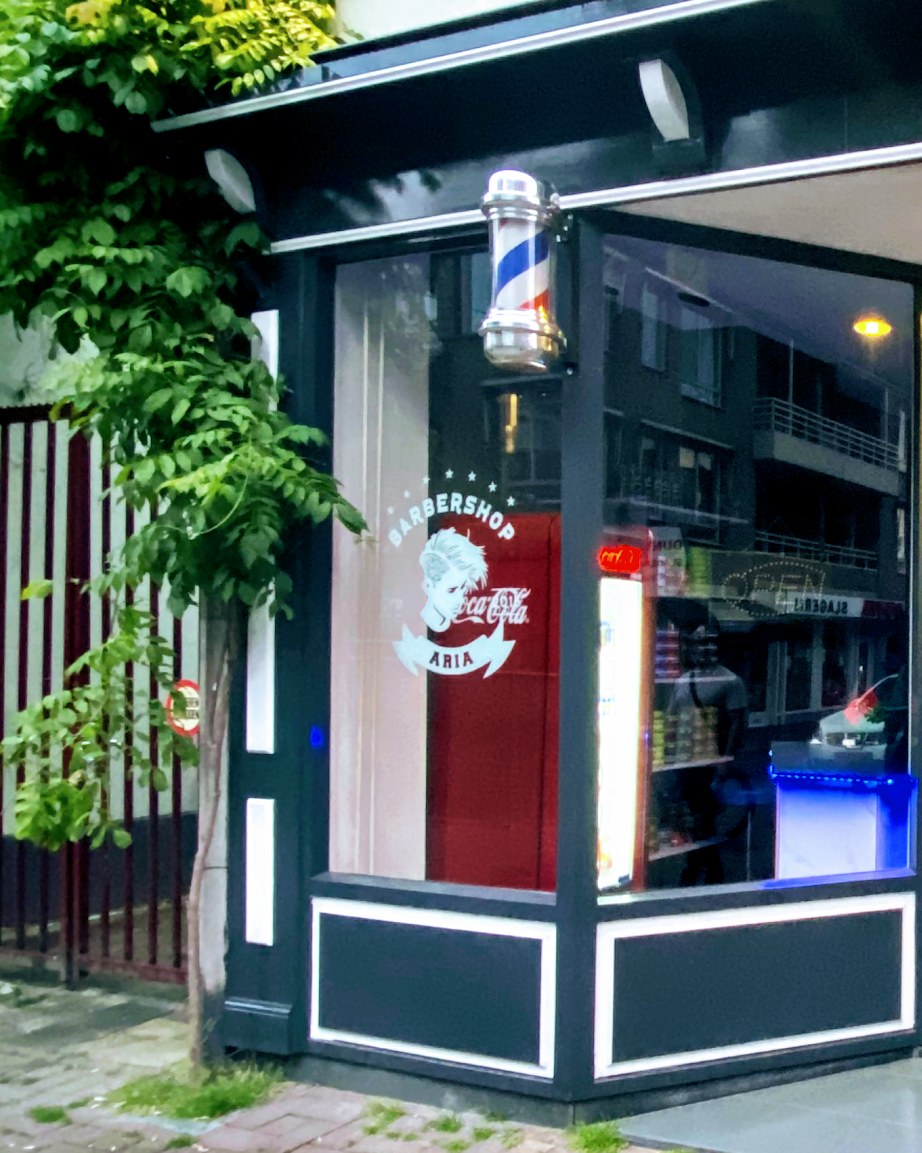 Etalage van Kapsalon Aria aan de Haagdijk met kapperspaal en raamletters
