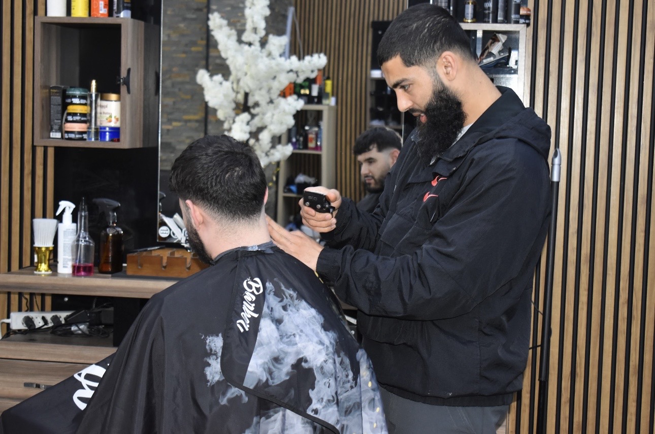 Een barbier van Kapsalon Aria knipt een klant in de shop