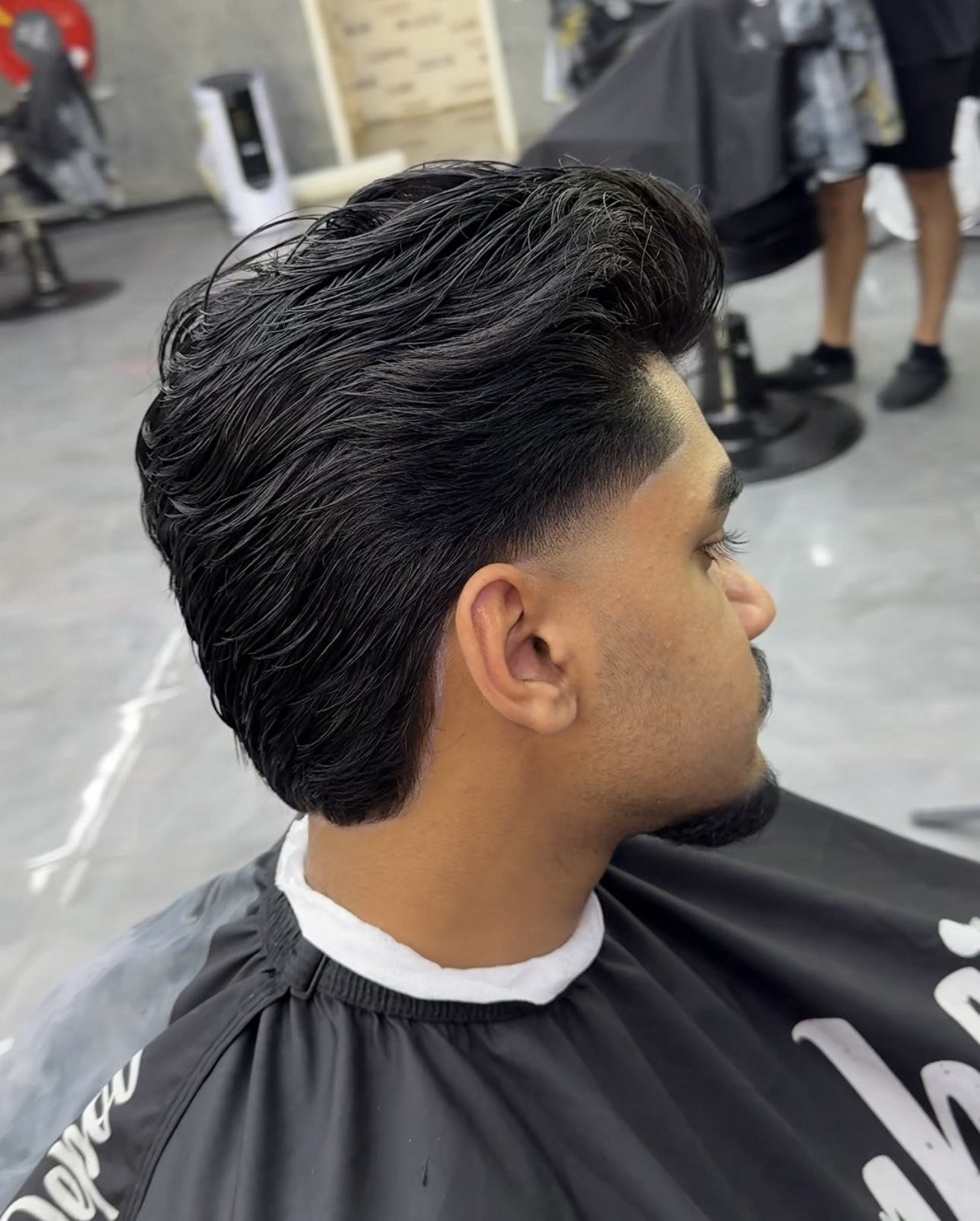 Opzij gekamde quiff met korte zijkanten, van opzij gezien